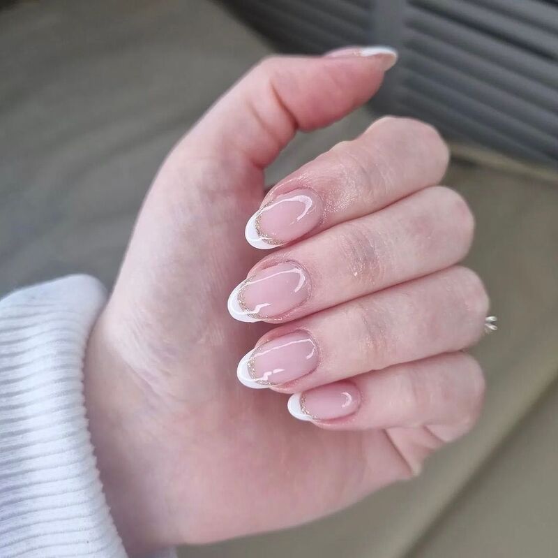 Credits: @beautyboutiquebymeg Via Instagram, una french manicure con glitter oro